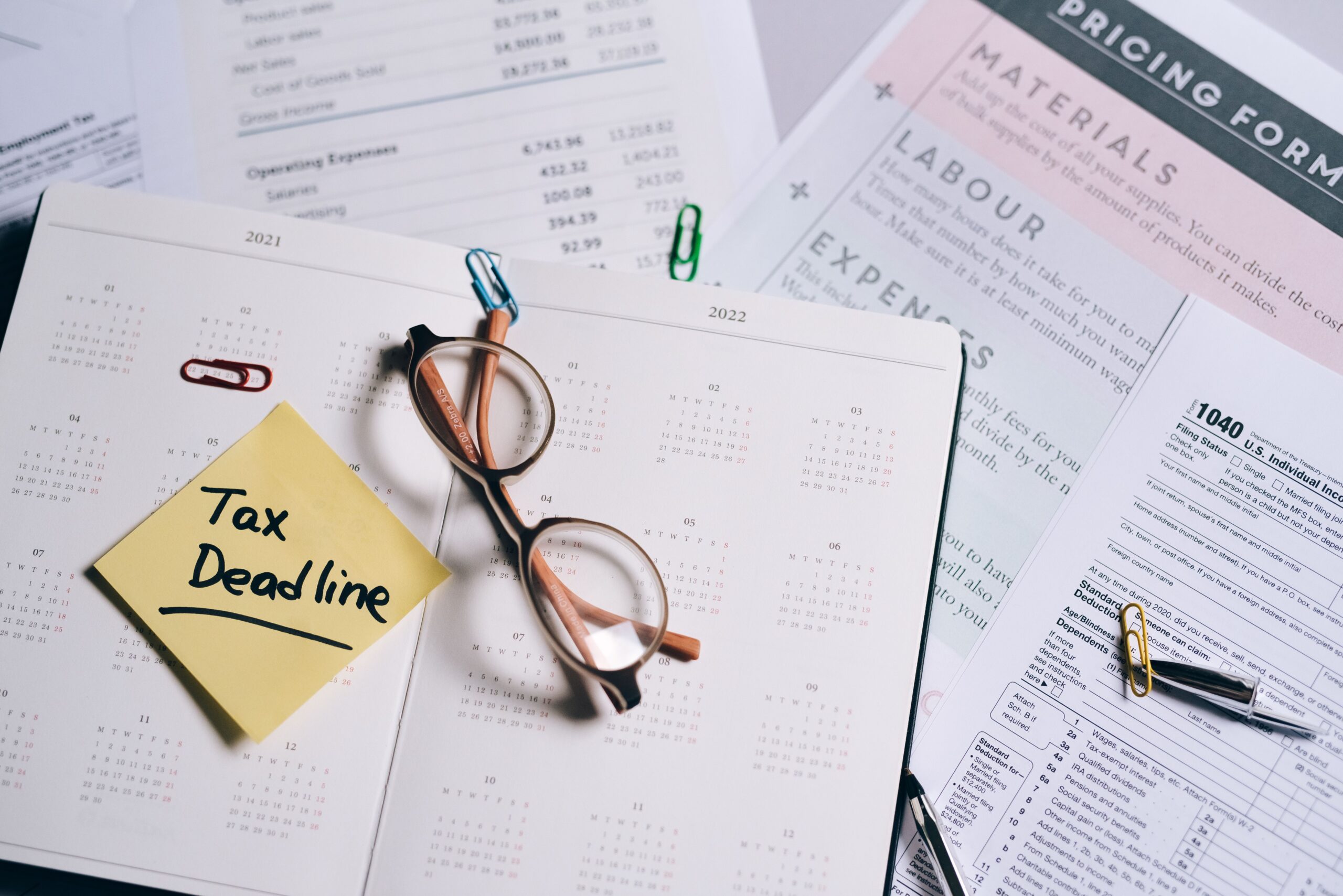 Tax deadline sticky note next to a 1040 form, reminder to prepare for tax season